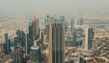 Aerial view of Dubai's skyline with high-rise buildings and iconic skyscrapers, set against a hazy sky, showcasing the modern architectural landscape of the city.