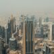 Aerial view of Dubai's skyline with high-rise buildings and iconic skyscrapers, set against a hazy sky, showcasing the modern architectural landscape of the city.