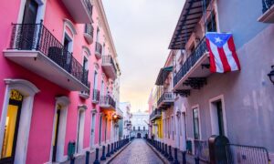 Street in puerto rico with pink builiding and flag hanging from balcony