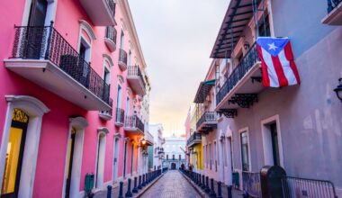 Street in puerto rico with pink builiding and flag hanging from balcony