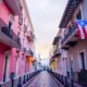 Street in puerto rico with pink builiding and flag hanging from balcony