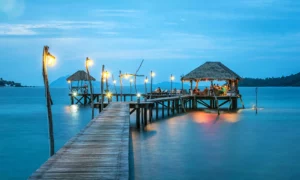 A serene tropical scene featuring a wooden pier extending over calm, turquoise water.